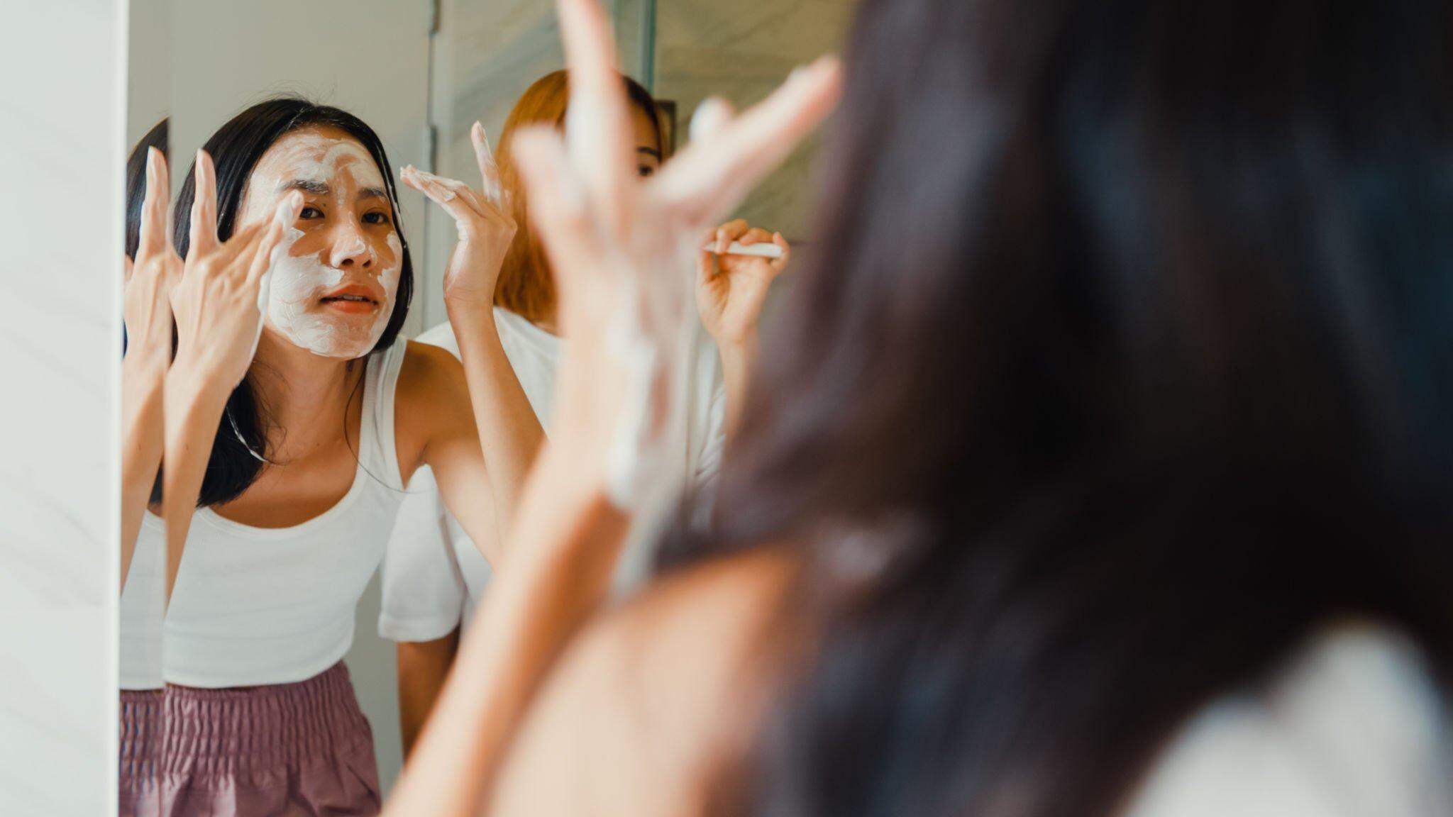 A girl doing skin care in front of mirror