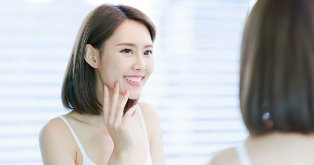 Young asian skin care woman smile and look mirror